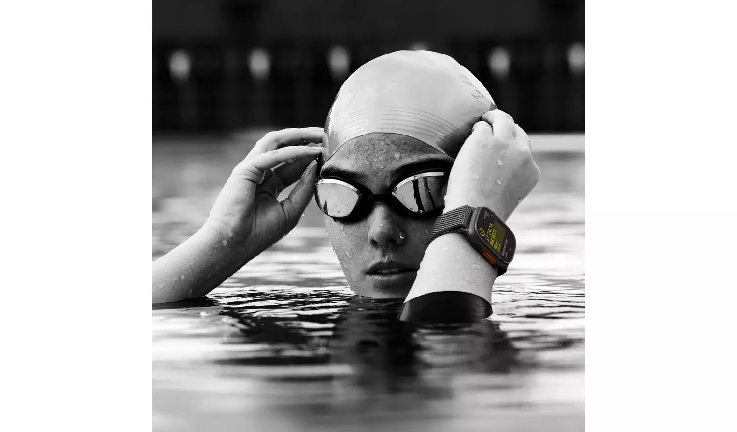 Smartwatch on swimmer’s wrist with black band and lit display, monochrome photo