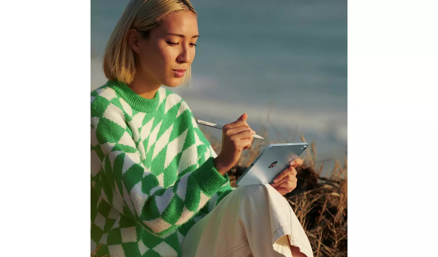 Woman using a blue iPad mini outdoors, tablet held in both hands