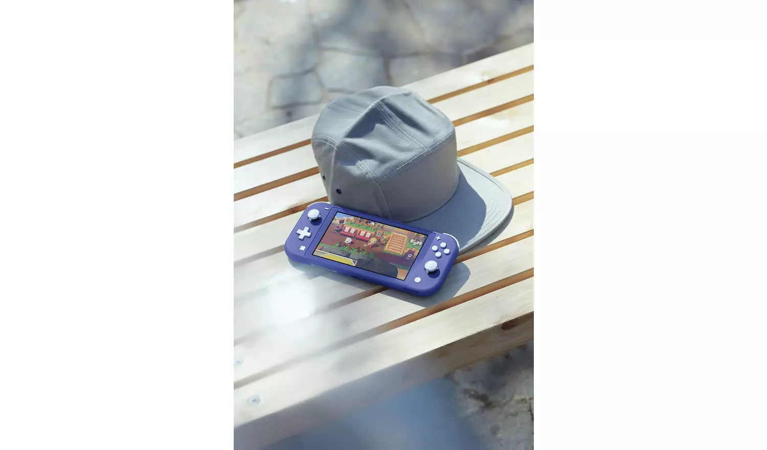 Nintendo Switch Lite blue console on a table with a hat beside it